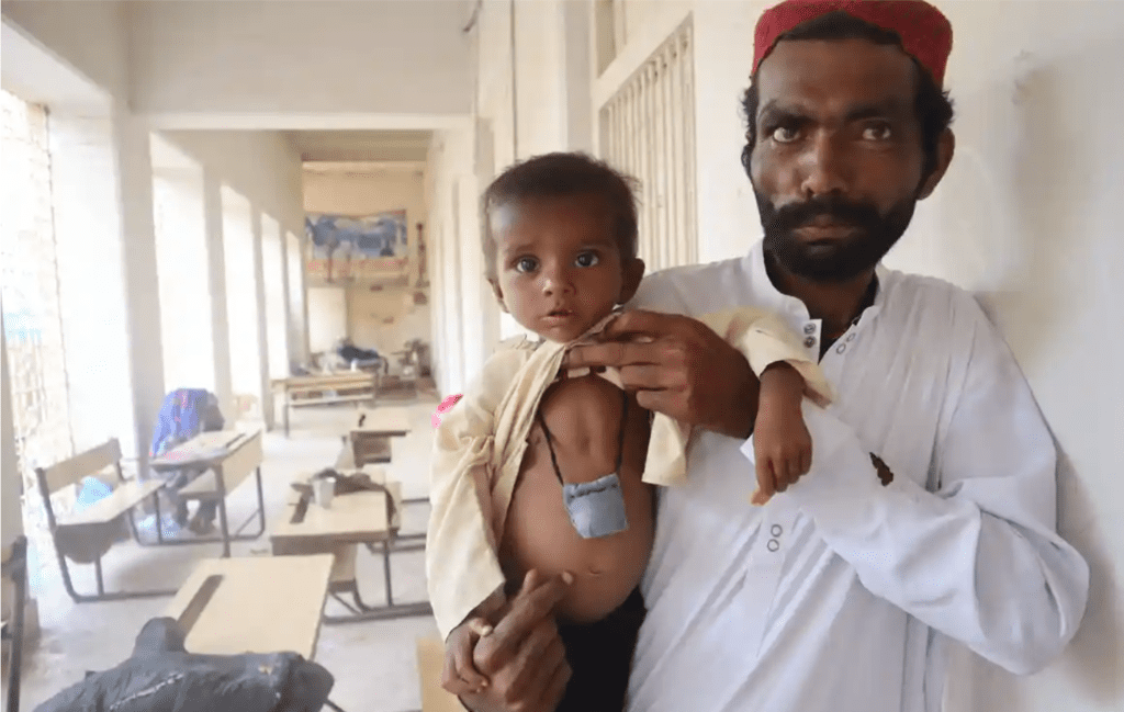 Image obtained from the Guardian © Shah Meer Baloch. This is Zeeshan Chandio with his son Nadeem Chandio, whose stomach has swollen from malnutrition during Pakistan's climate crisis. 