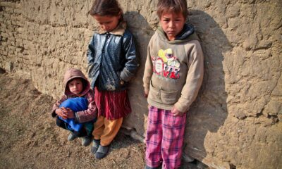 Afghani children with their backs against the wall.