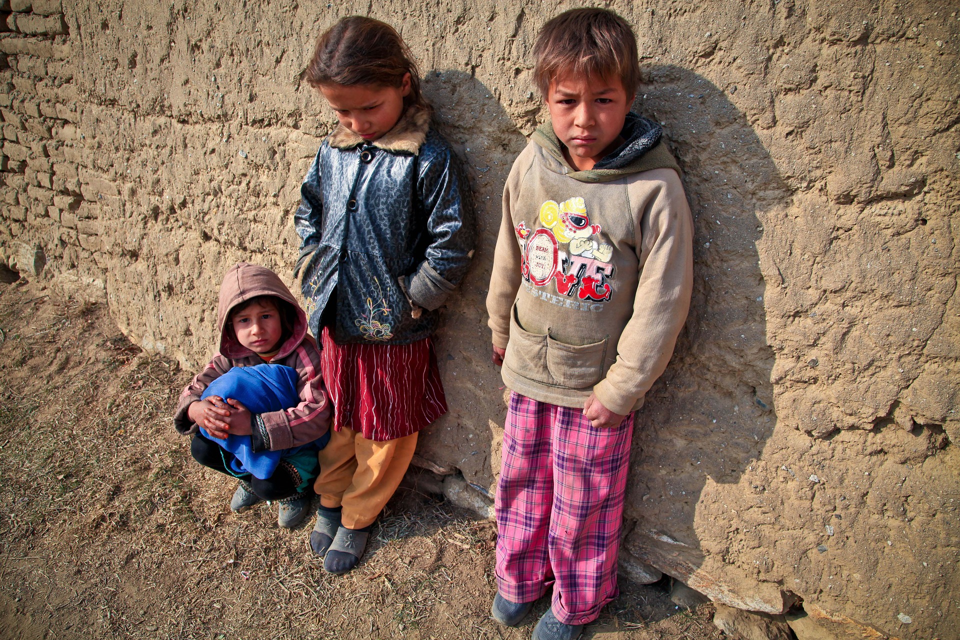 Afghani children with their backs against the wall.