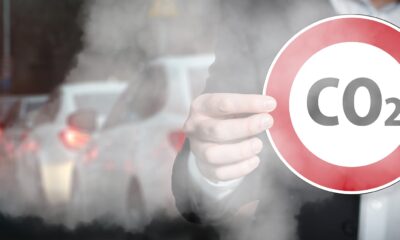 A man holding a Carbon Dioxide sign while standing in traffic fumes
