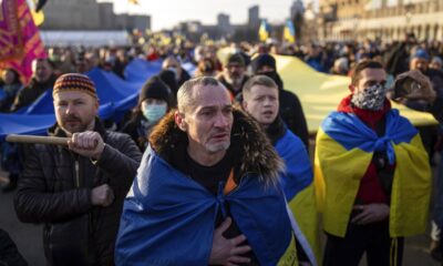 A demonstrator cries listening to a national anthem as other rallies with Ukrainian national flags in the centre of Kharkiv, Ukraine's second-largest city