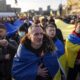 A demonstrator cries listening to a national anthem as other rallies with Ukrainian national flags in the centre of Kharkiv, Ukraine's second-largest city
