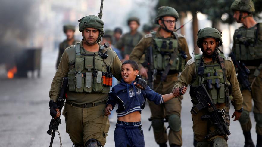 IDF soldiers arresting a Palestinian child.