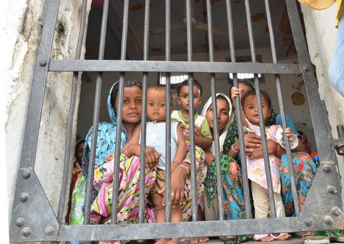 Children standing behind bars in a Jail.